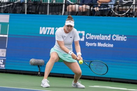 Tennis player prepares to return a serve during a WTA event, showcasing talent and intensity on court.