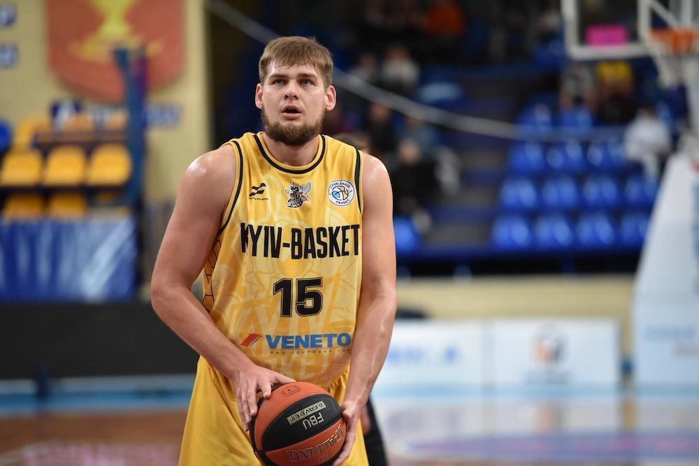 Олександр Ковляр у жовтому формі Yiyv-Basket в момент виконання штрафного кидка, демонструючи видатні навички у баскетболі.