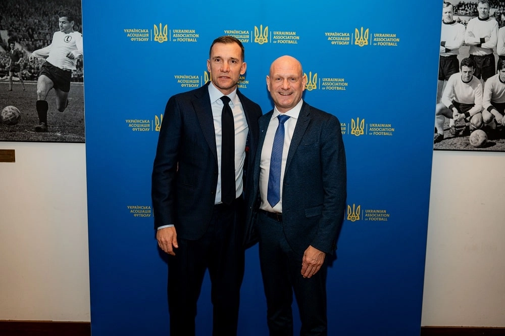 Відомі особистості футболу України на фоні логотипу Української асоціації футболу в атмосфері урочистої події.