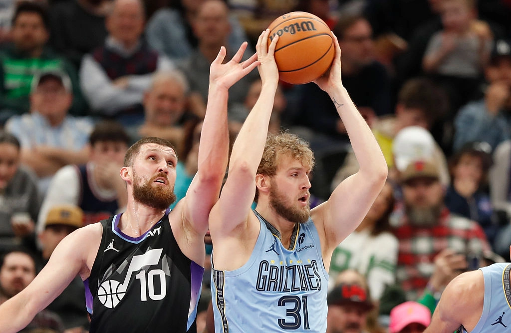 Grizzlies player shoots as Utah defender closes in during a thrilling NBA match. Intense on-court action and strategy unfold.