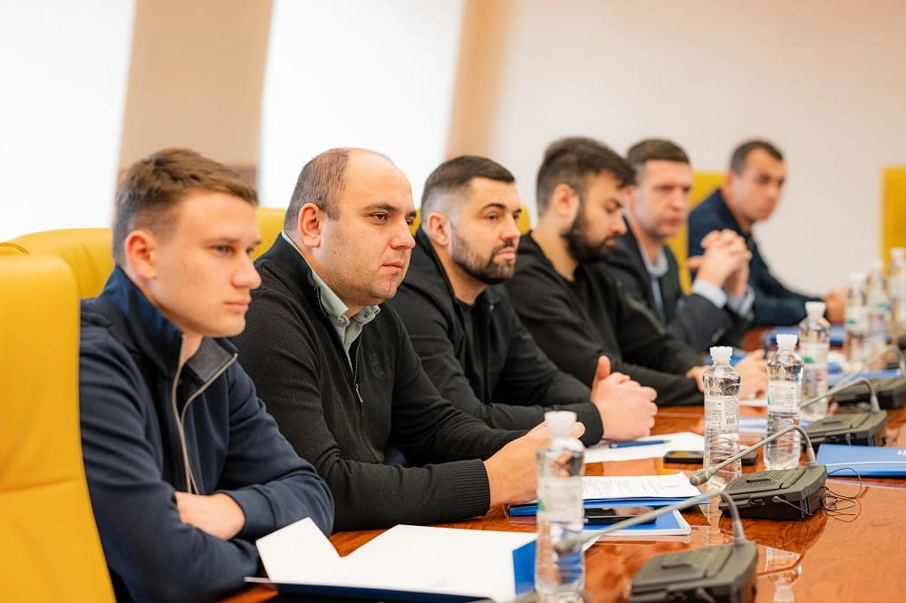 Учасники засідання Комітету масового футболу УАФ за столом з документами та пляшками води