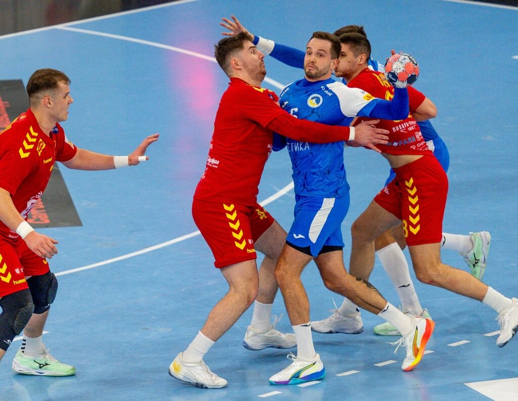 Гравець збірної України в синій формі намагається пройти захист гравців Північної Македонії в червоній формі