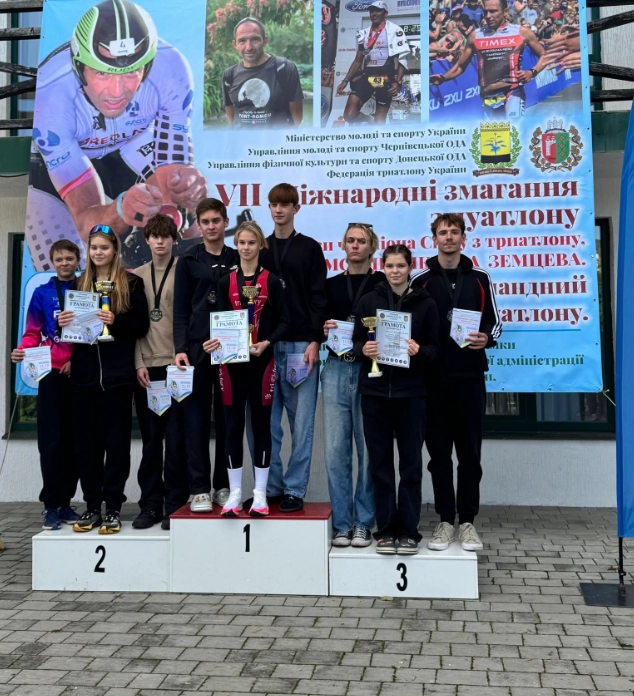 Команда переможців на podium міжнародного чемпіонату України з триатлону у Боянах, з медалями та дипломами.