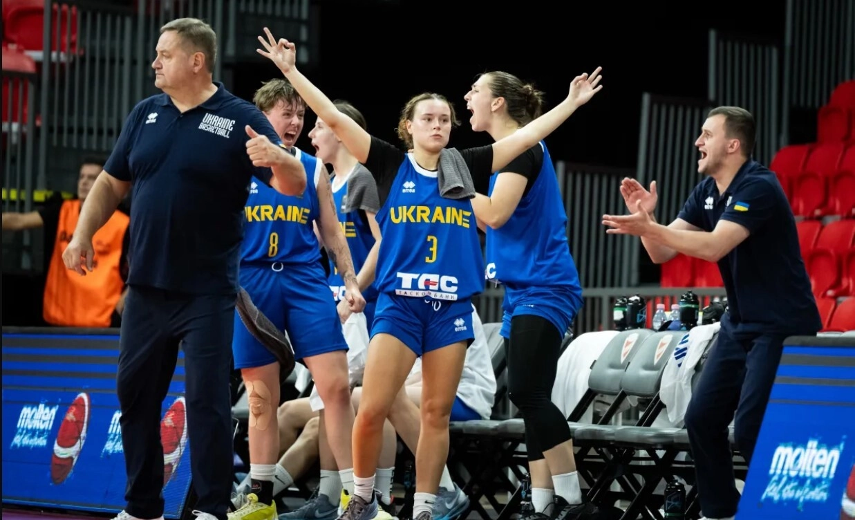 Ukrainian basketball player Serafima Tykhyi celebrates with teammates during a game, showcasing teamwork and enthusiasm.