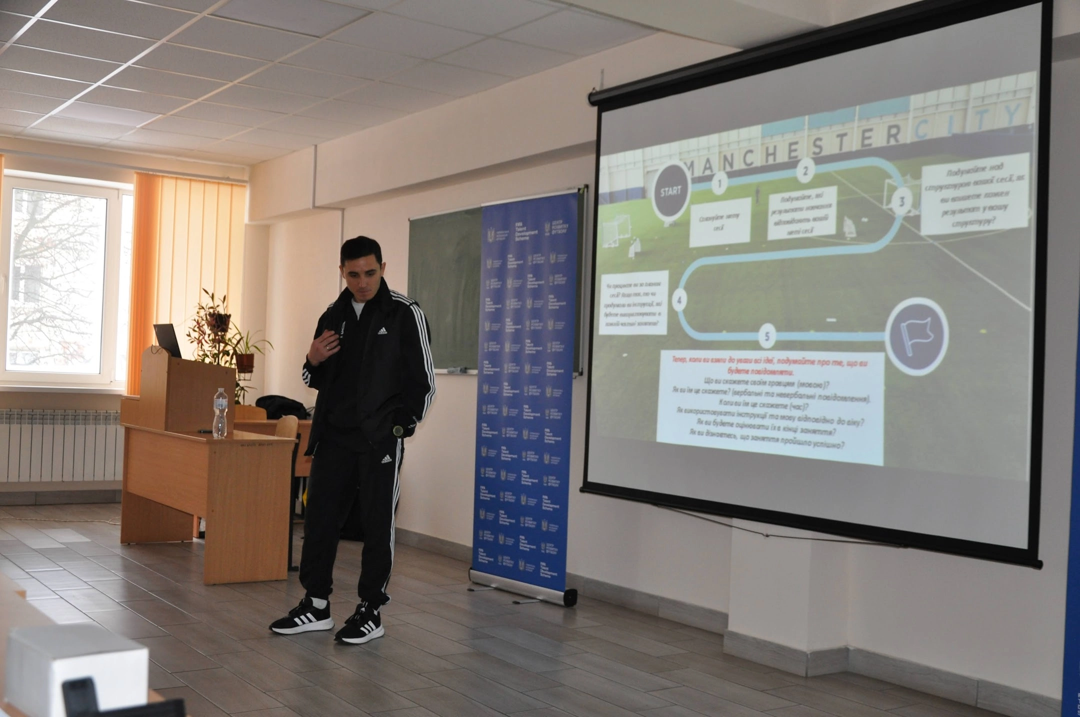 Лектор у спортивному костюмі проводить презентацію про методологію «Манчестер Сіті» на семінарі в Чернівцях