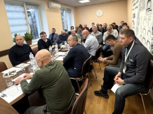 Учасники конференції ФСПУ в Києві обговорюють новий статут організації, сидячи за столом у залі