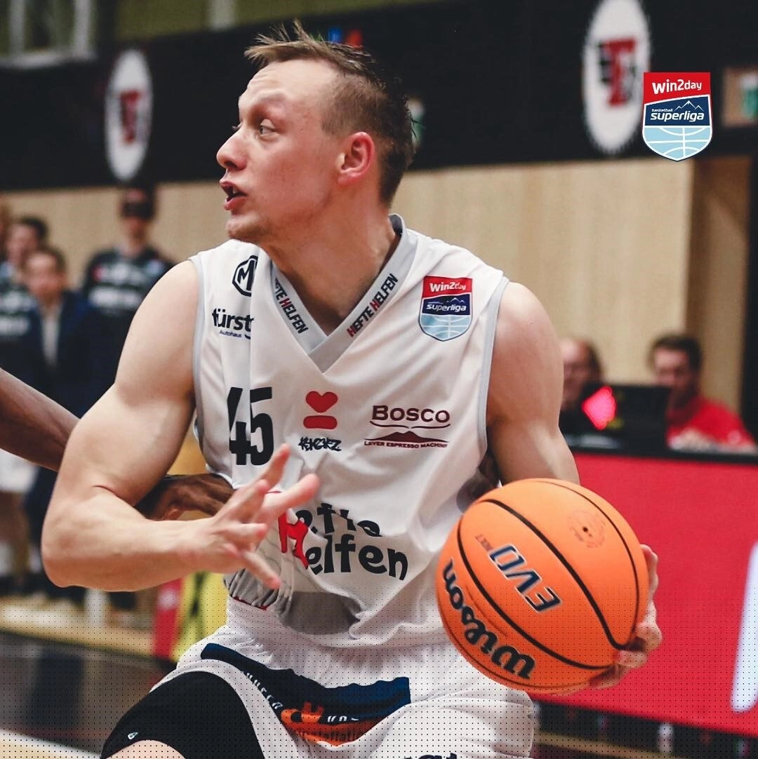 Basketball player with ball navigating through defence during a match, showcasing skill and determination on the court.