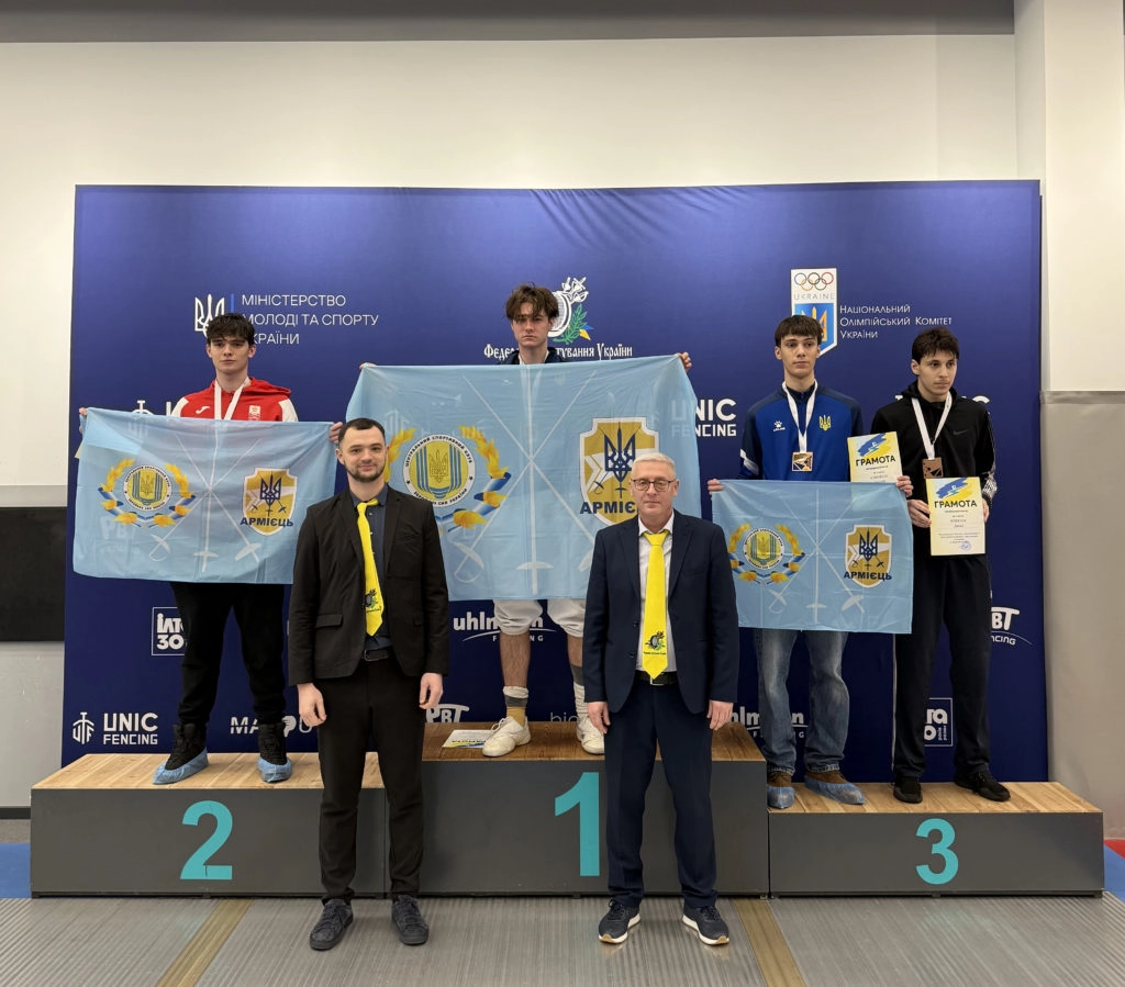 Winners of the Ukrainian junior fencing championships celebrate on the podium, showcasing flags and medals.