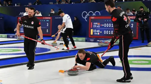 Канадська команда з керлінгу під час матчу на зимових Олімпійських іграх, гравці в чорній формі