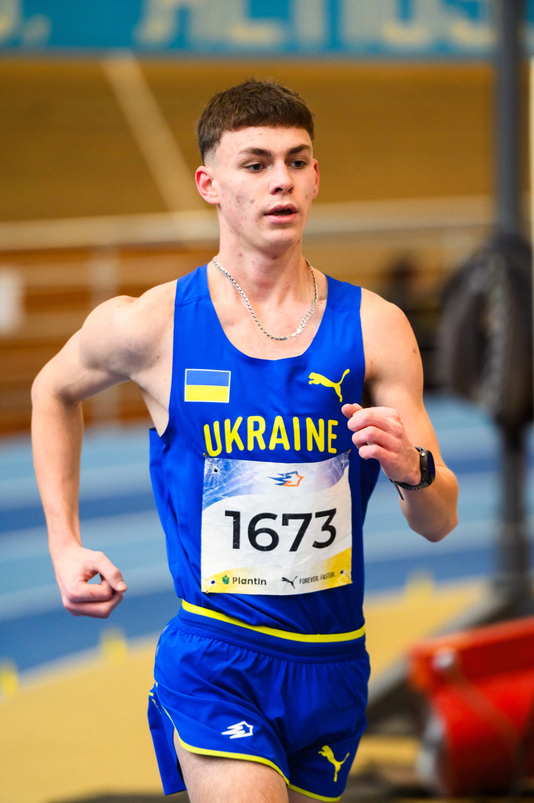 Юнак у синій формі з номером 1673 біжить в приміщенні на чемпіонаті України з легкої атлетики у Львові