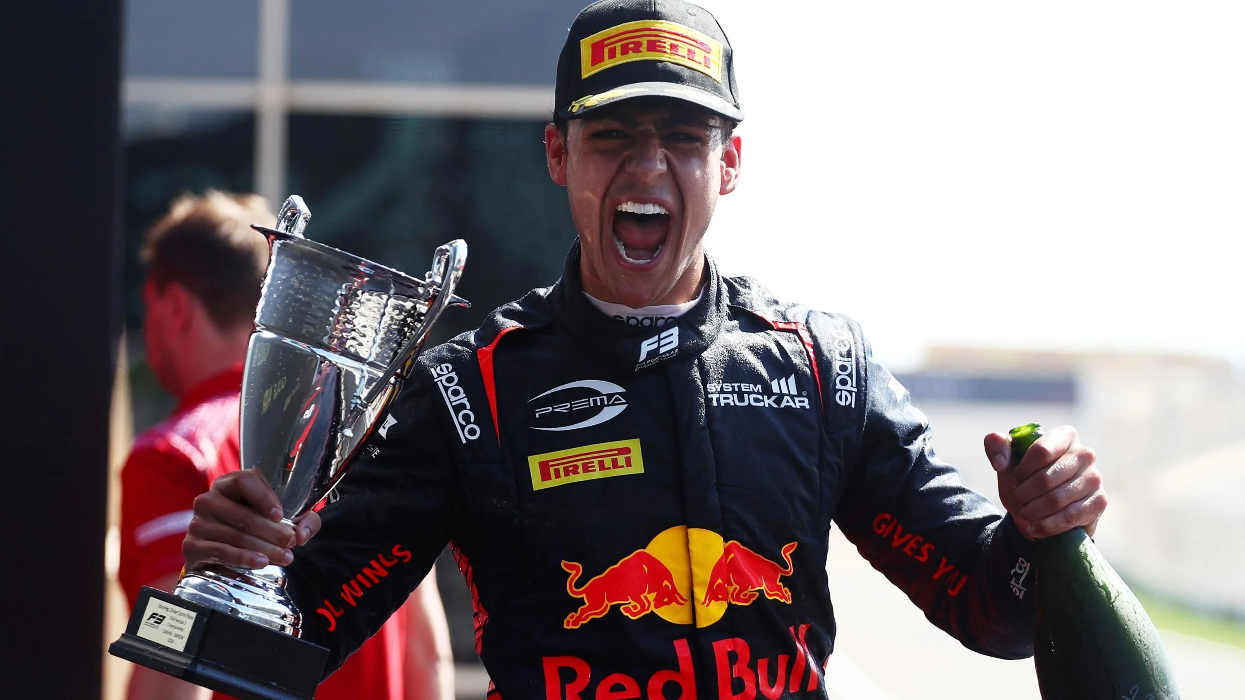 Молодий гонщик у формі Red Bull тримає трофей, радіючи перемозі на гоночному треку