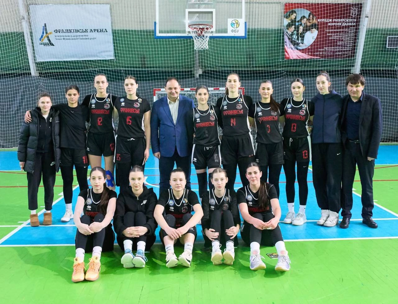 Жіноча баскетбольна команда в чорній формі позує на майданчику перед фіналом Кубка України