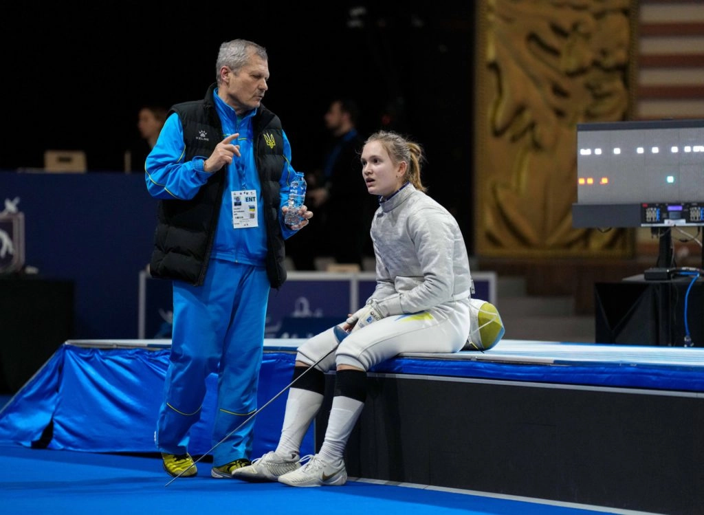 Майя Величко в екіпіровці сидить на лаві поруч з тренером під час чемпіонату Європи з фехтування