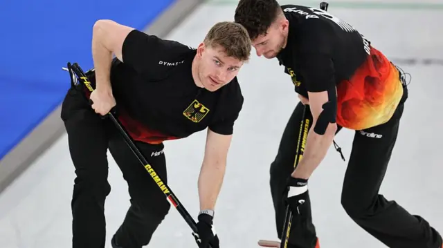 Німецькі спортсмени під час змагань з керлінгу, зосереджені на грі на льоду