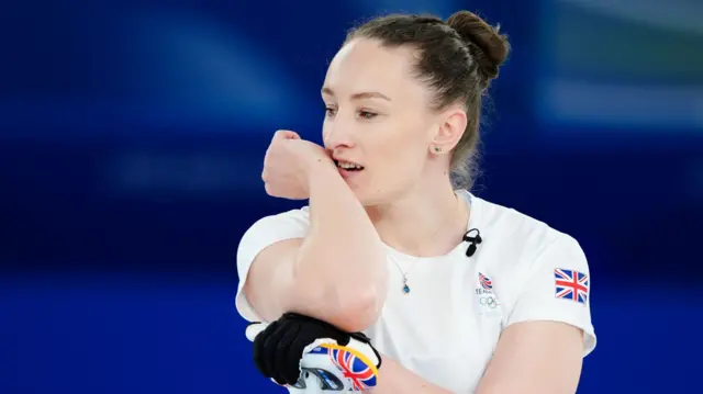 Спортсменка з команди Великобританії в білій формі зосереджено дивиться вбік під час змагань