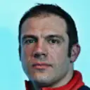 Чоловік у спортивній куртці на синьому фоні, можливо, пов'язаний зі скелетоном або зимовими видами спорту