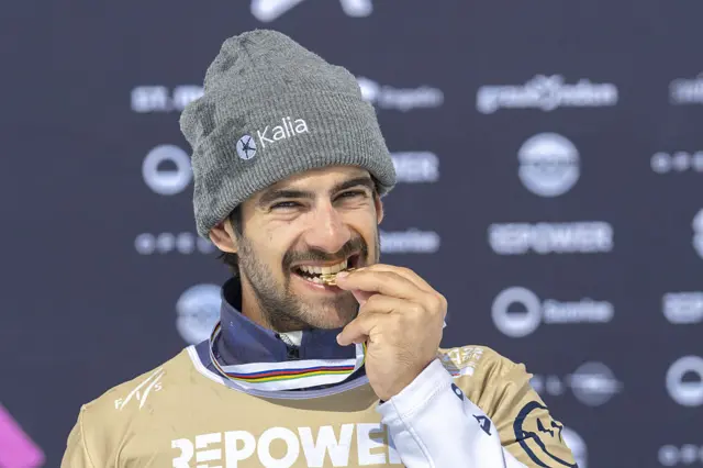 Спортсмен у шапці кусає медаль на церемонії нагородження після змагань зі скелетону