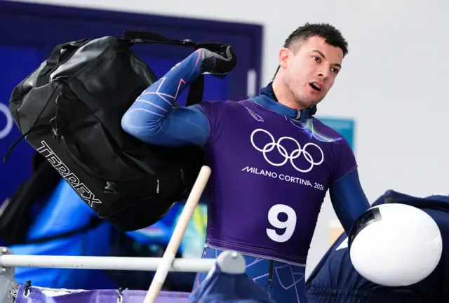 Британський скелетоніст тримає шолом і сумку на Олімпійських іграх у Мілані-Кортіна 2026