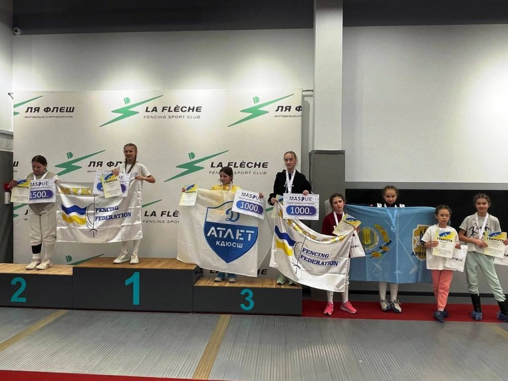 Юні фехтувальники на п'єдесталі з нагородами та прапорами клубів на турнірі «Ля Флєш Cup» у Києві