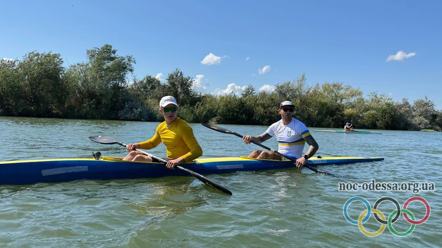 Двоє байдарочників у жовтих футболках тренуються на водоймі під час підготовки до змагань