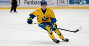 Хокеїст у жовтій формі з ключкою на льоду під час матчу, зосереджений на грі