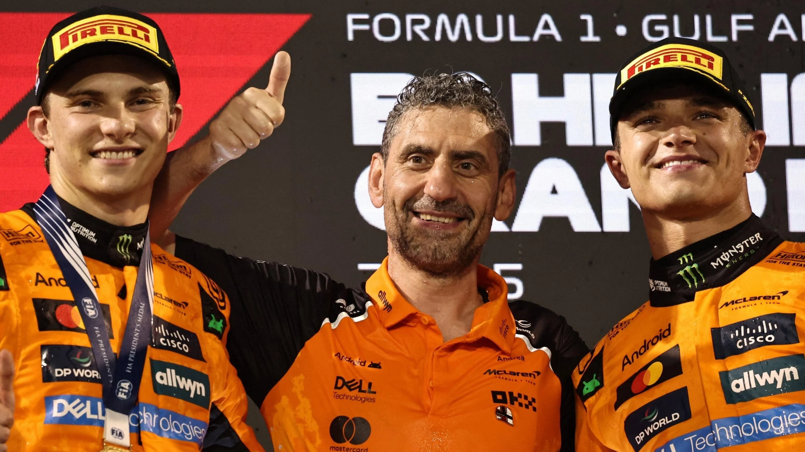 Двоє гонщиків McLaren та їхній керівник святкують перемогу на подіумі Формули 1 в Абу-Дабі