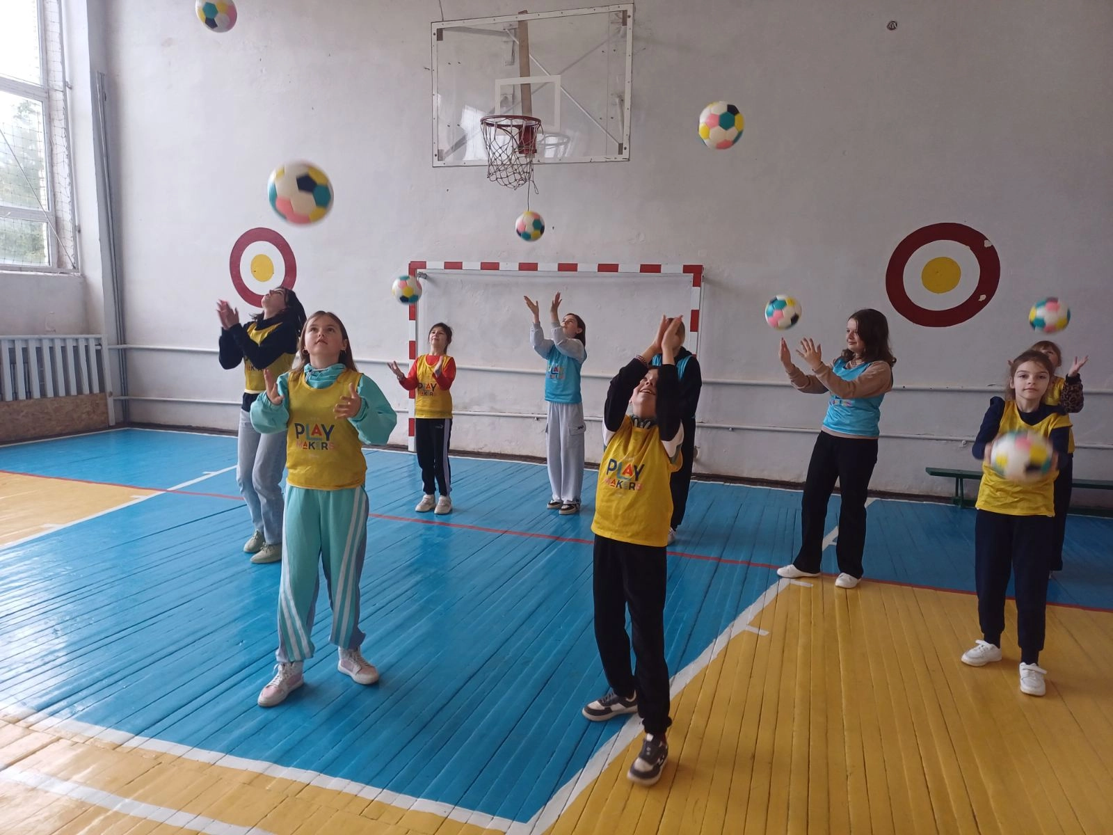 Діти в спортивній залі кидають м'ячі вгору під час тренування UEFA Playmakers у Зборові