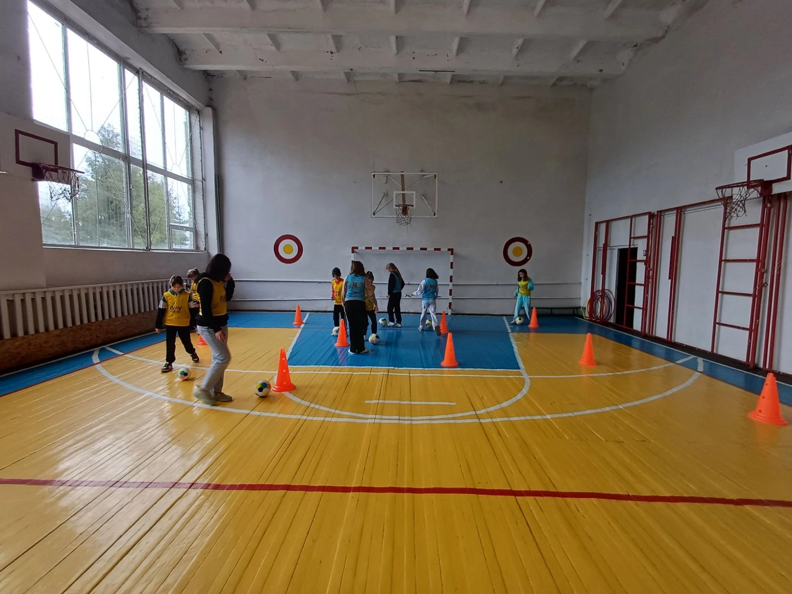 Діти тренуються з м'ячами в спортивній залі під час програми UEFA Playmakers у Зборові