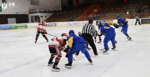 Хокеїсти у синій формі збірної України U18 проти суперників у червоній формі на льодовій арені