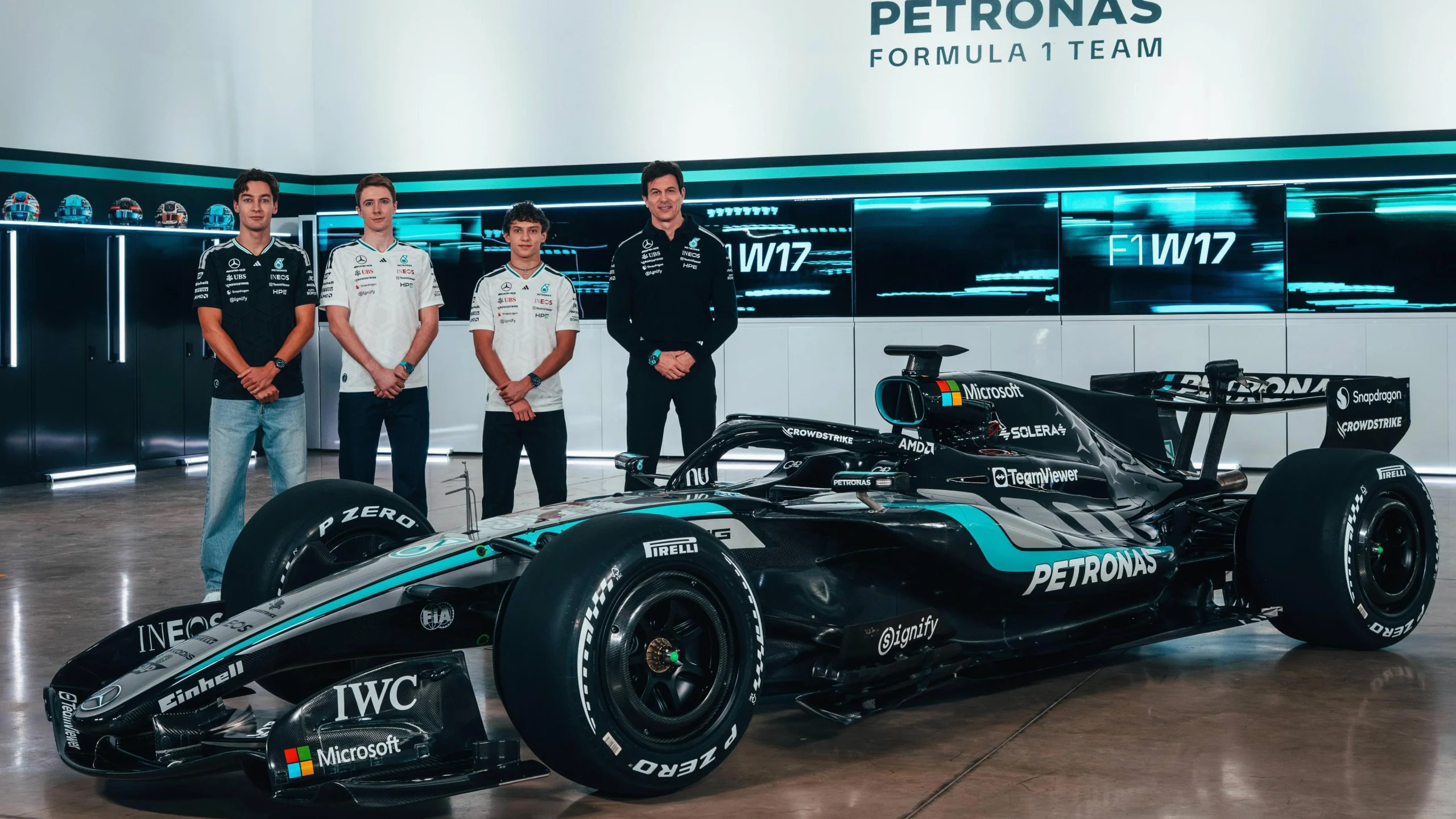 Гоночний болід Mercedes F1 з пілотами команди на фоні стенду Petronas Formula 1 Team