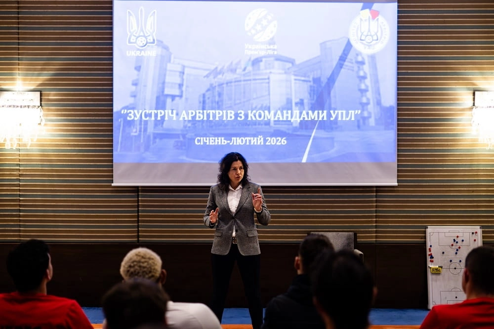 Жінка виступає перед аудиторією на фоні екрану з написом "Зустріч арбітрів з командами УПЛ