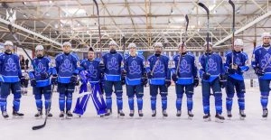 Хокейна команда у синій формі стоїть на льоду, готуючись до матчу в спортивній арені