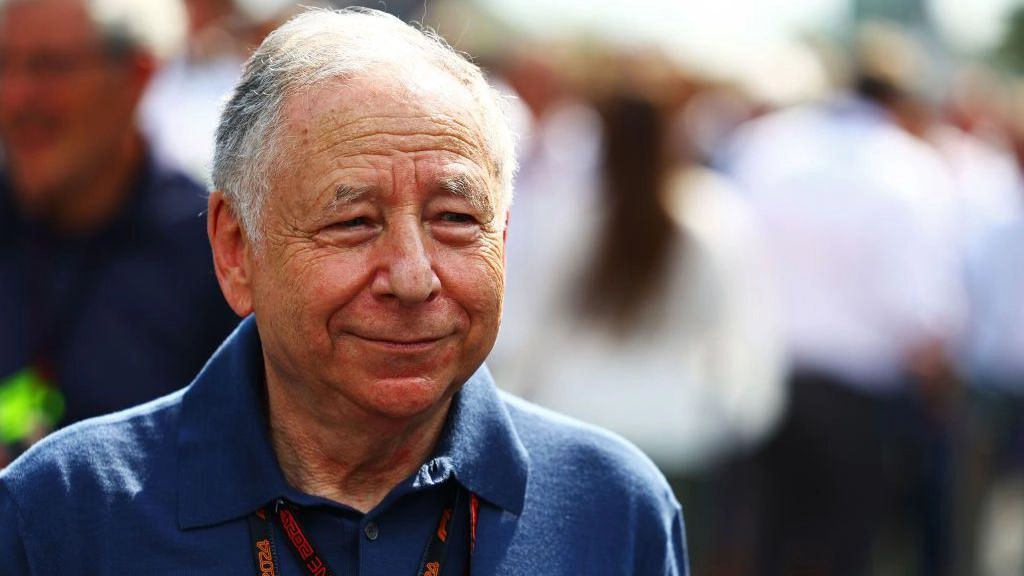 Колишній президент FIA Жан Тодт на спортивному заході, одягнений у синю сорочку, посміхається