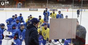 Хокеїсти в синій та жовтій формі слухають тренера на льодовій арені під час тренування