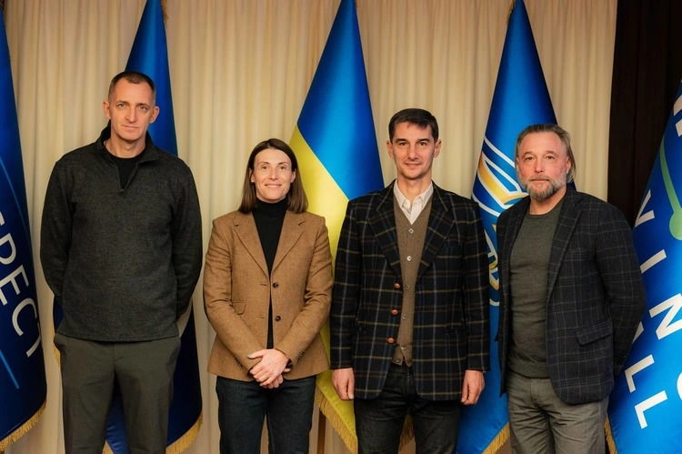 Чотири людини стоять перед прапорами України та УАФ під час зустрічі тренерів жіночих збірних