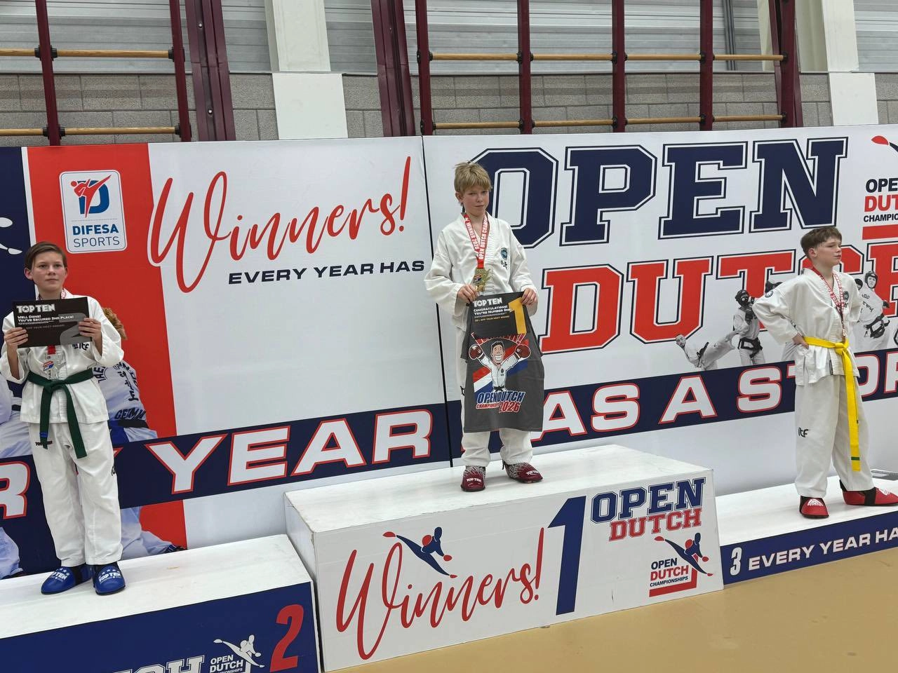 Три юні спортсмени на п'єдесталі пошани Open Dutch Championship 2026 у кімоно з медалями
