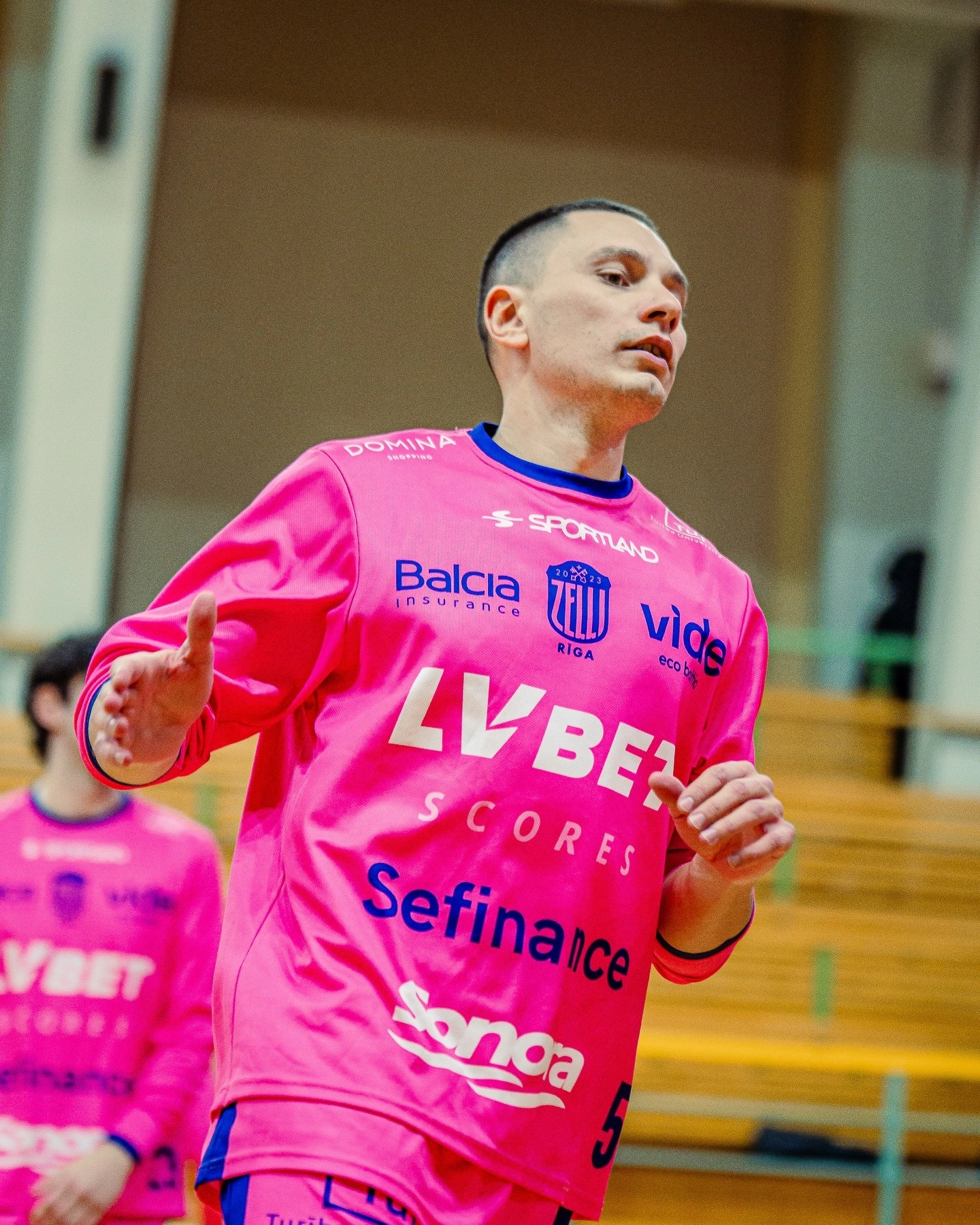 Баскетболіст у рожевій формі команди LV BET під час розминки перед матчем у спортивному залі