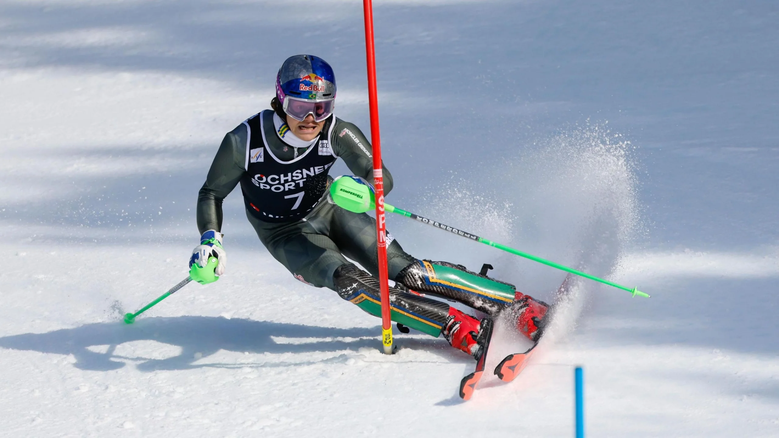 Лижник у шоломі та окулярах виконує слаломний спуск на змаганнях з гірськолижного спорту