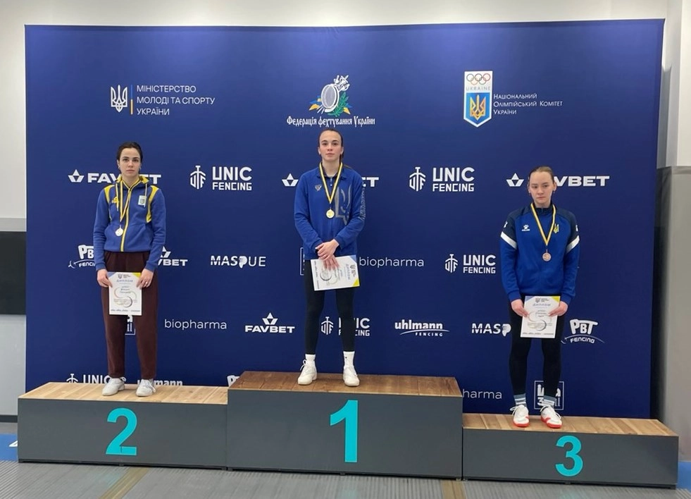 Три спортсменки на п'єдесталі пошани з медалями після змагань з фехтування на шаблях у Києві