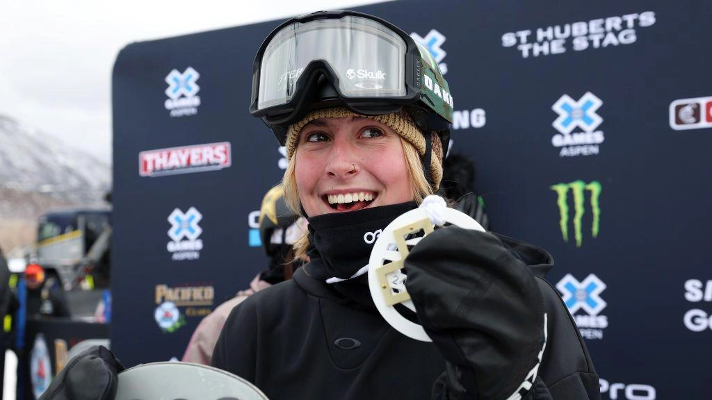 Спортсменка з медаллю на фоні банера X Games, усміхнена, в шоломі та окулярах