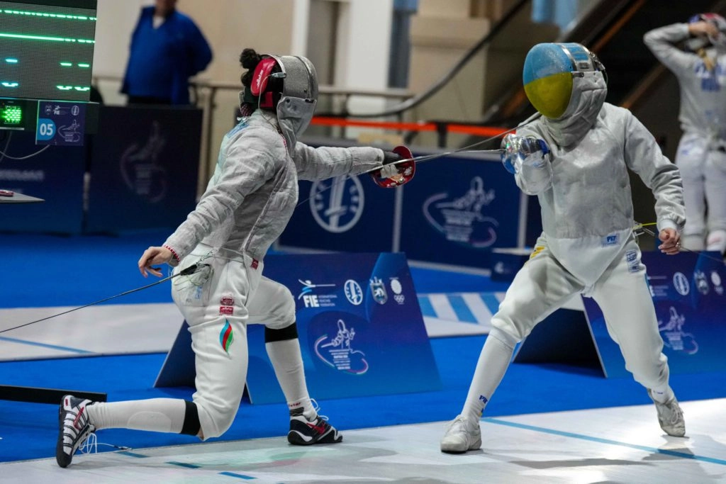 Шпажистка в білому костюмі атакує суперницю на чемпіонаті Європи в Тбілісі, Грузія