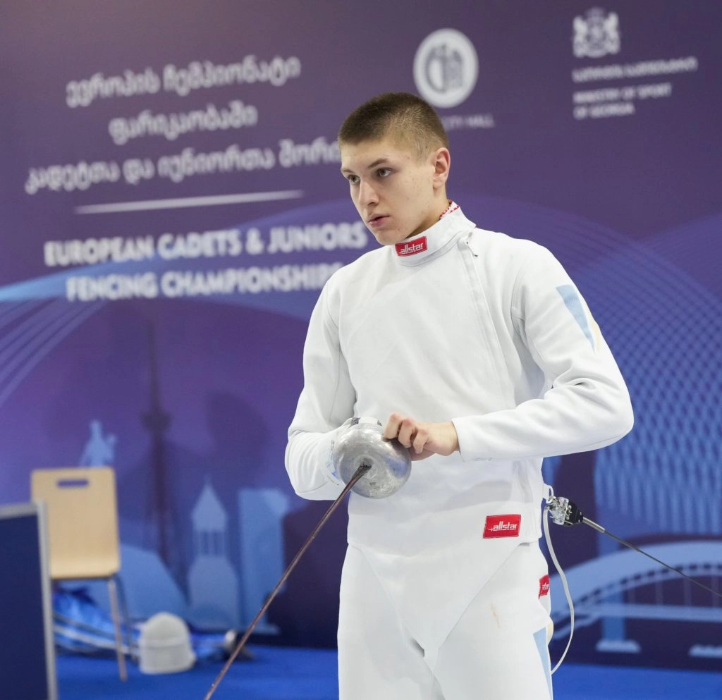 Юний шпажист у білому костюмі готується до поєдинку на чемпіонаті Європи в Тбілісі