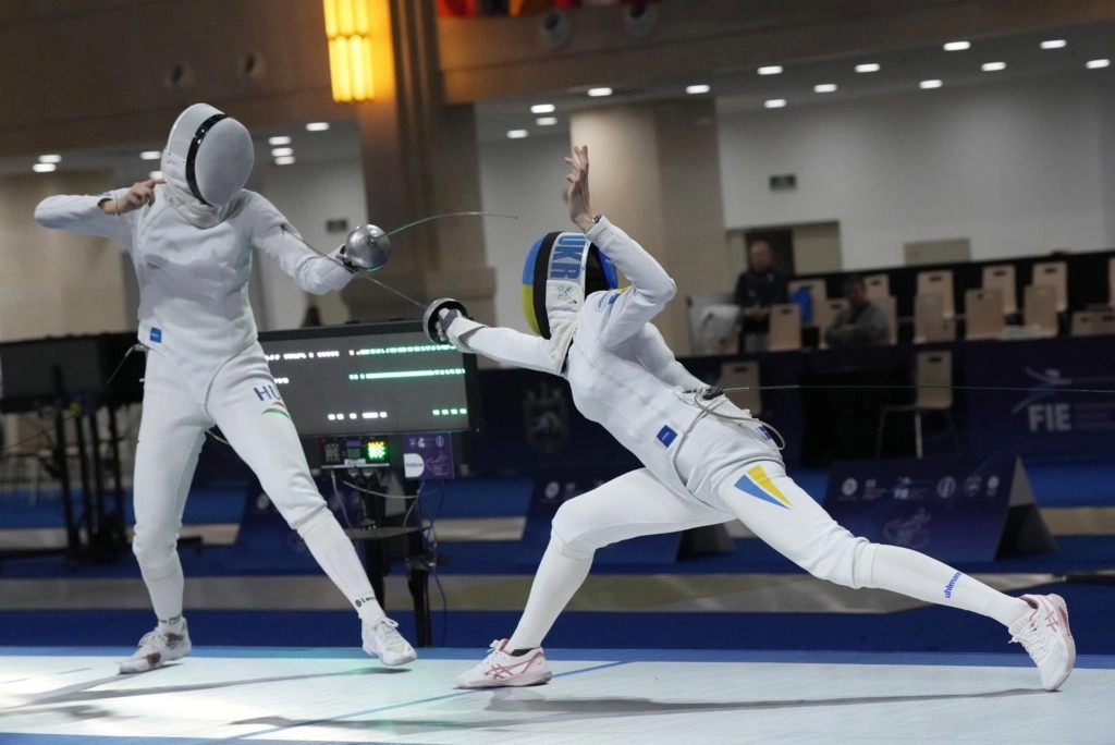 Українська шпажистка в білому костюмі атакує суперницю на чемпіонаті Європи в Тбілісі