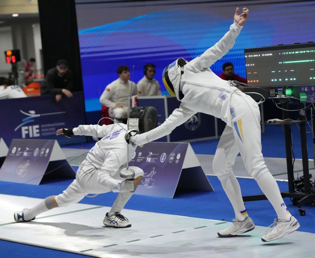 Двоє фехтувальників у білому екіпіруванні змагаються на чемпіонаті Європи у Тбілісі