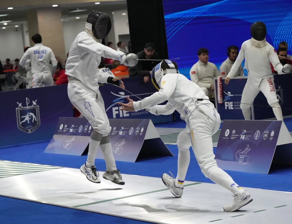 Двоє фехтувальників у білому екіпіруванні змагаються на чемпіонаті Європи у Тбілісі