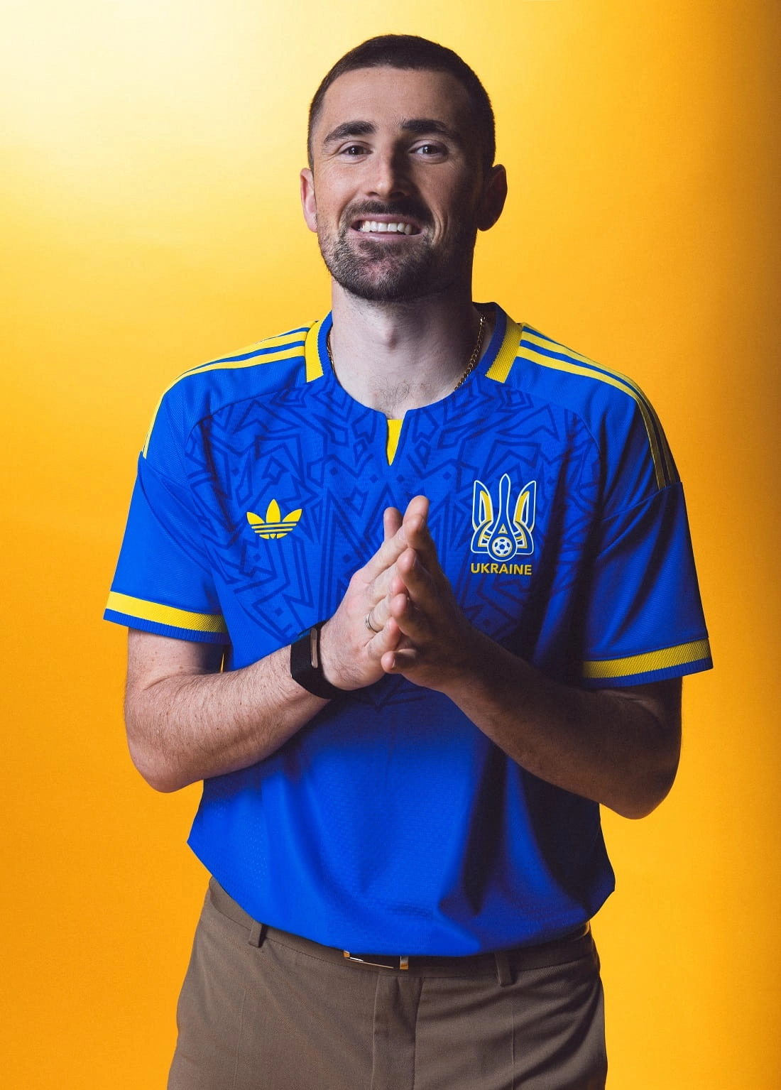 Чоловік у новій синій виїзній формі збірної України з футболу від adidas на жовтому фоні