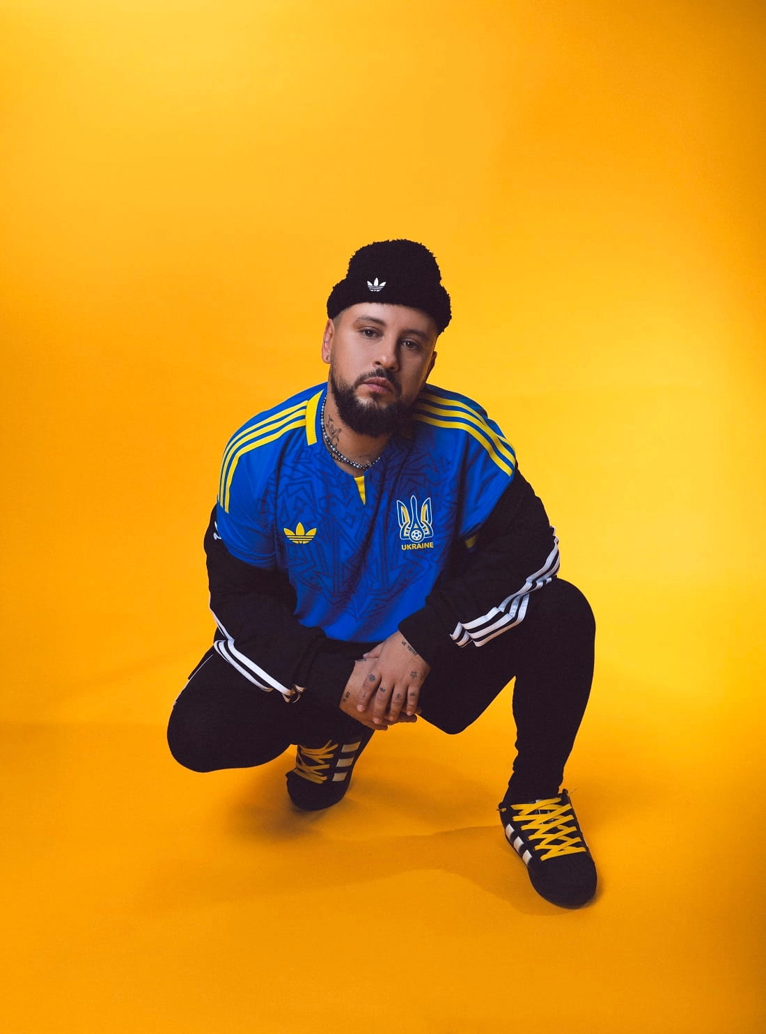 Чоловік у синій футбольній формі збірної України від adidas на жовтому фоні