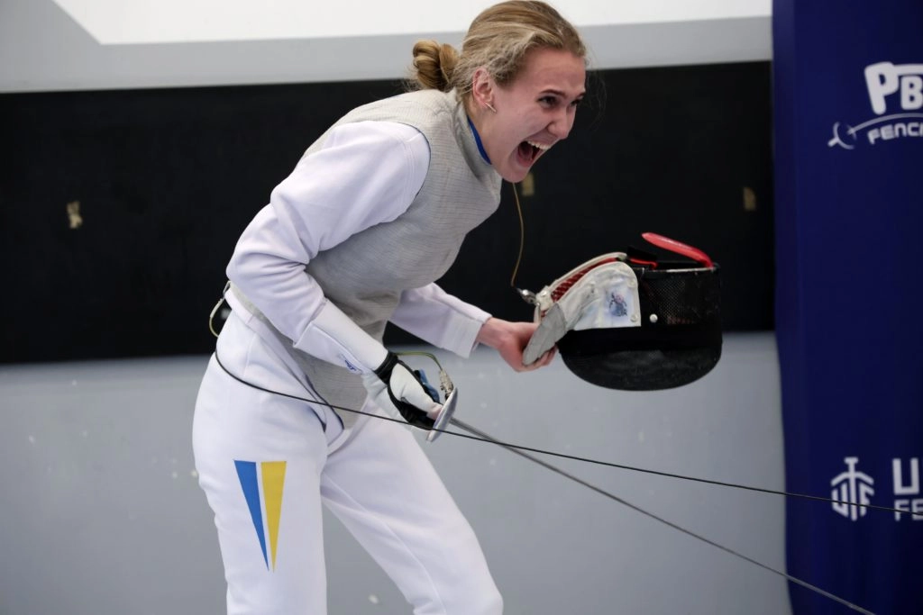 Фехтувальниця в білому костюмі радіє перемозі на чемпіонаті України U-23 у фехтувальному клубі «Ля Флєш