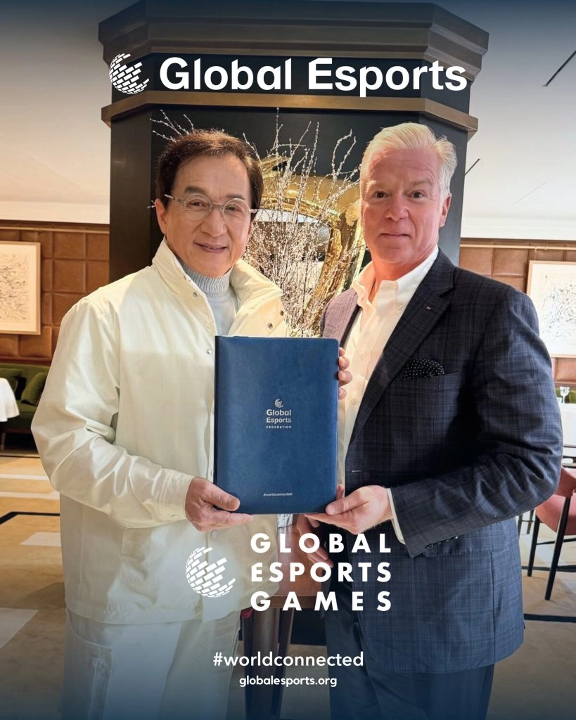 Легендарний актор тримає документ Global Esports Federation разом з іншим чоловіком