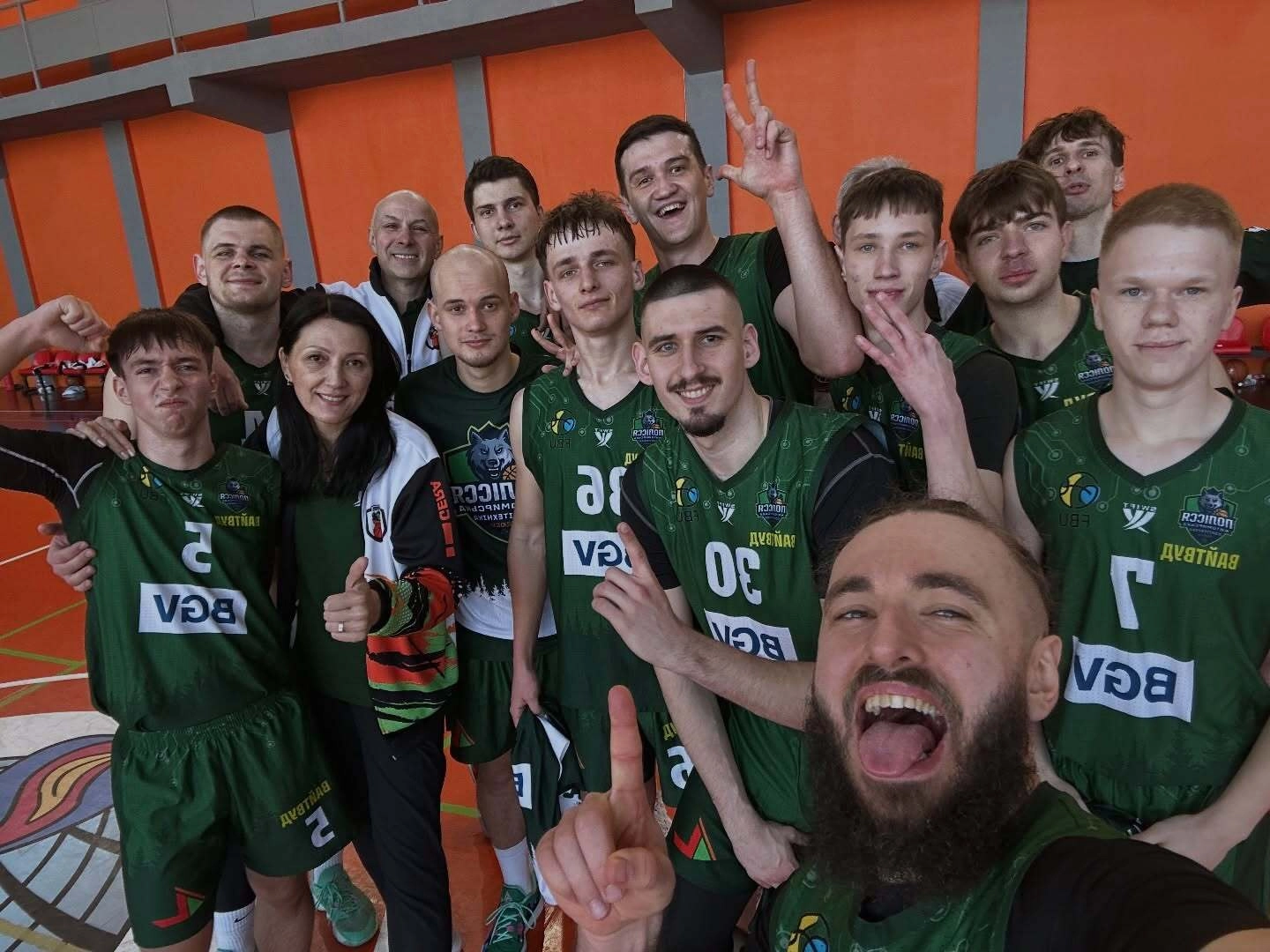 Баскетбольна команда святкує перемогу на змаганнях у спортивному залі, гравці в зеленій формі